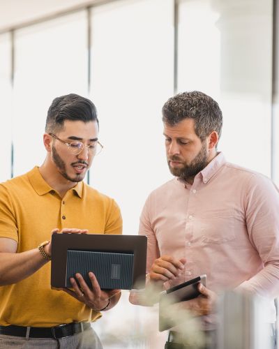 Eine Person zeigt etwas auf einem Tablet einer andere Person.